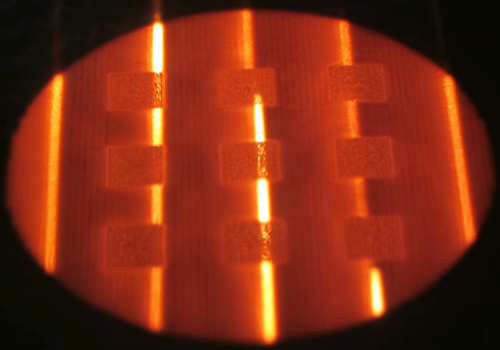 Electron Beam Melting (EBM) powder bed during part building (benchmark cubes) using the electron beam for the pre-heating phase. - Electron Beam Melting (EBM) powder bed during part building (benchmark cubes) using the electron beam for the pre-heating phase.